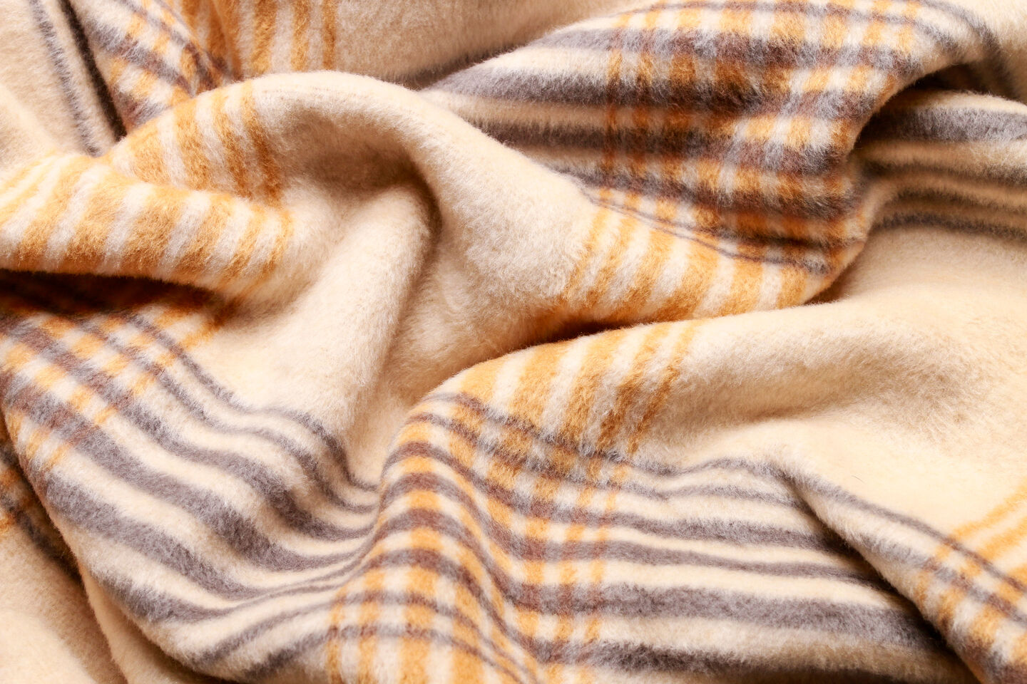A plaid-patterned wool blanket draped over a fluffy white bed, exuding warmth and inviting comfort in a softly lit room. A plaid-patterned wool blanket draped over a fluffy white bed, exuding warmth and inviting comfort in a softly lit room.
